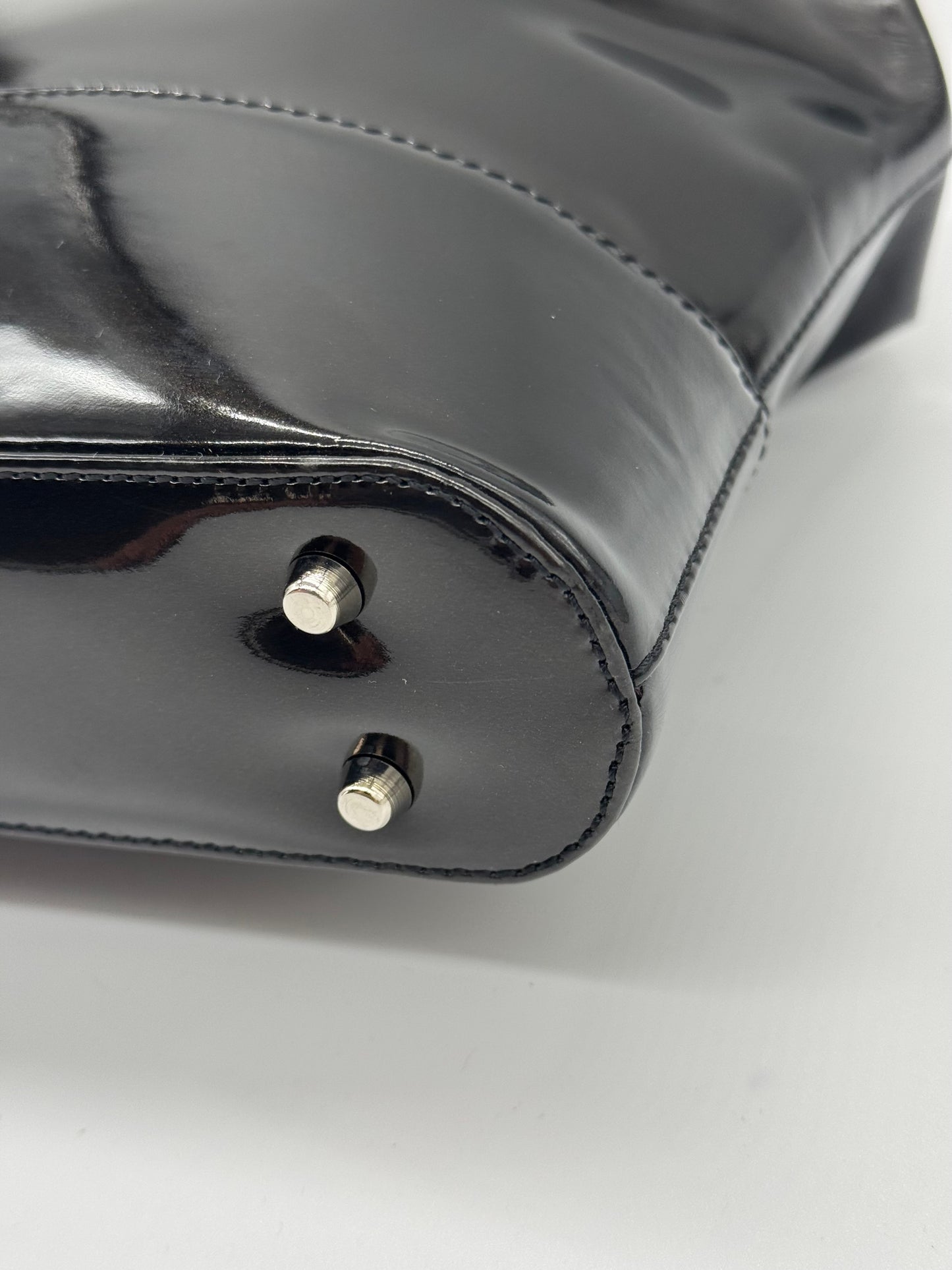 Dettaglio della base di una borsa a mano Borse Vintage Gianni Versace in pelle verniciata nera con piedini metallici