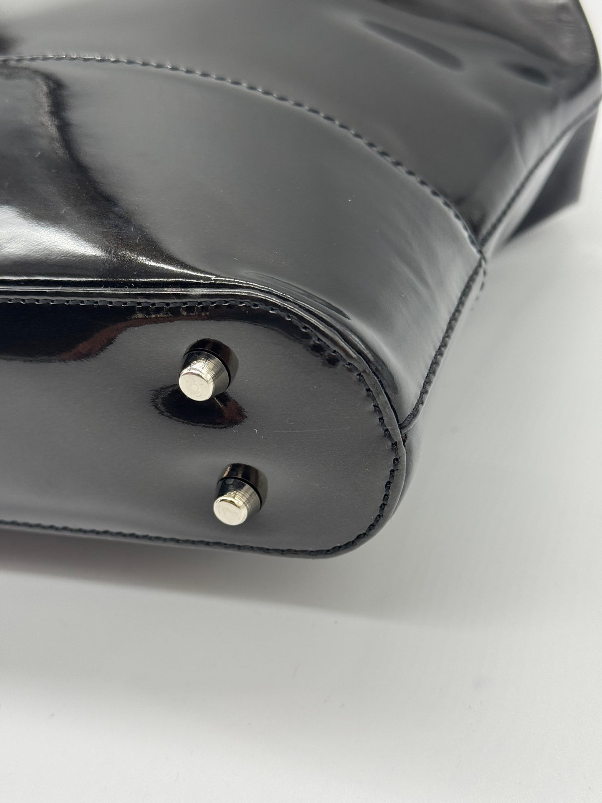 Dettaglio della base di una borsa a mano Borse Vintage Gianni Versace in pelle verniciata nera con piedini metallici
