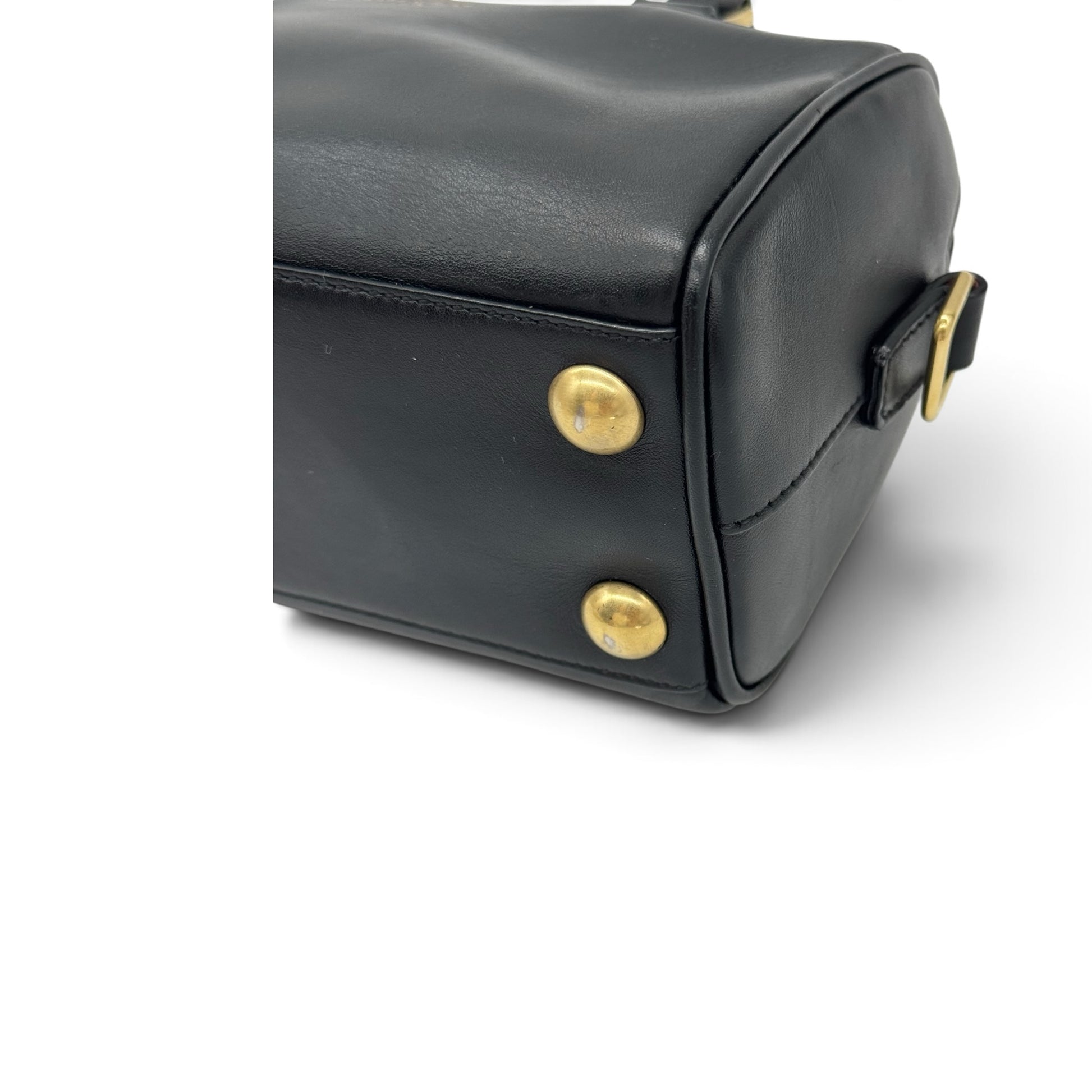 Dettaglio del fondo di una borsa a mano Borse Vintage in pelle nera con piedini protettivi in metallo dorato.