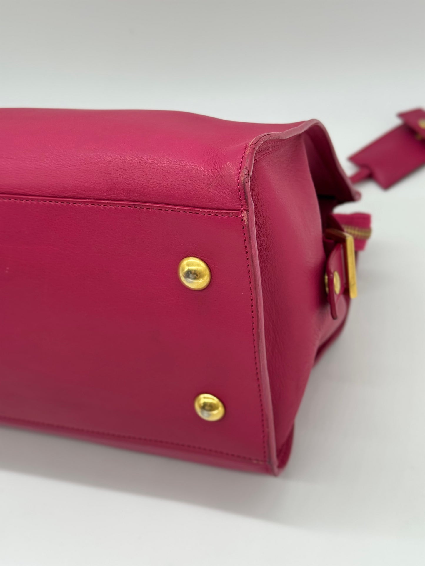 Dettaglio della base in pelle fucsia della borsa Borse Vintage Saint Laurent con piedini protettivi in metallo dorato