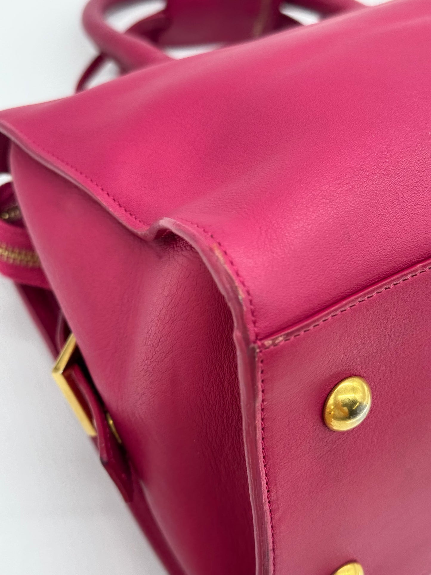 Dettaglio della base in pelle fucsia di una borsa Borse Vintage Saint Laurent con piedini protettivi dorati