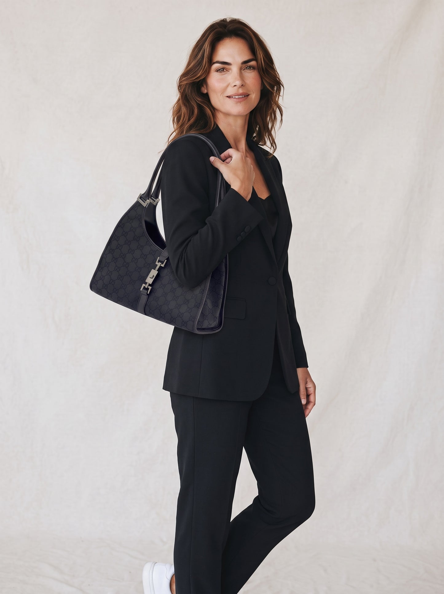 Modella indossa borsa a spalla Borse Vintage Gucci Jackie in tessuto nero con motivo GG e dettagli in pelle