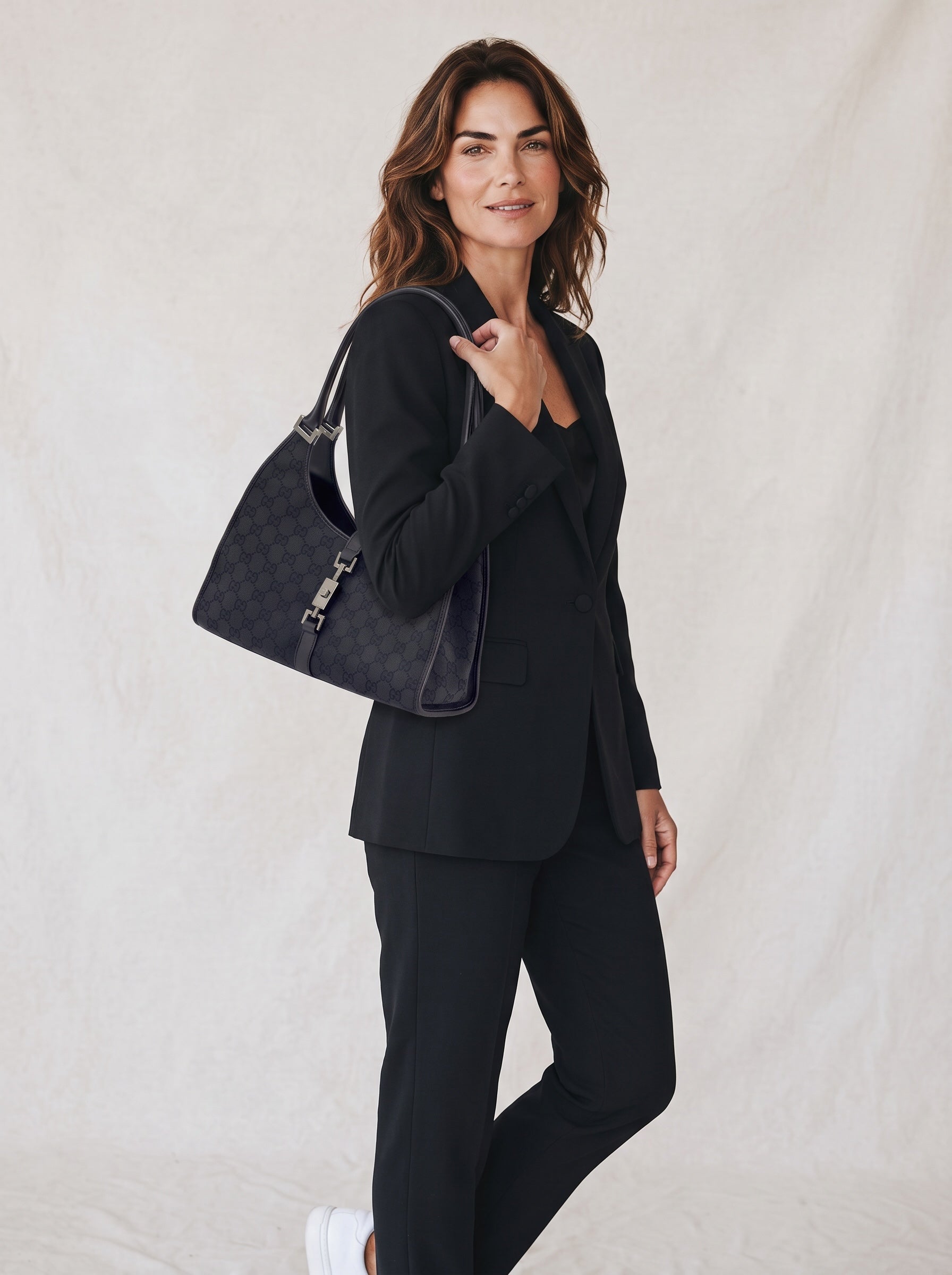 Modella indossa borsa a spalla Borse Vintage Gucci Jackie in tessuto nero con motivo GG e dettagli in pelle