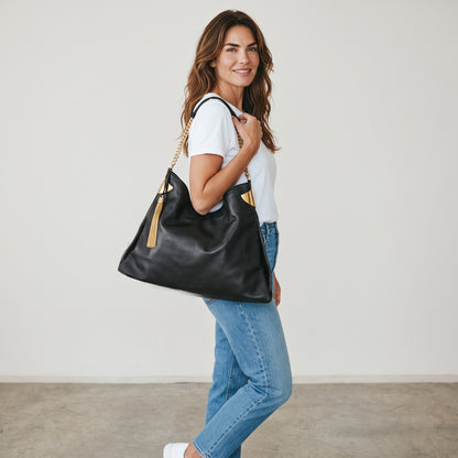 Modella indossa borsa a spalla Borse Vintage Gucci in pelle nera con tracolla a catena dorata e nappa decorativa