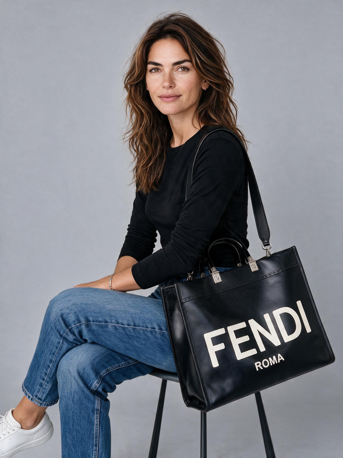 Modella seduta con borsa tote Fendi nera in pelle con logo bianco, proposta da Borse Vintage