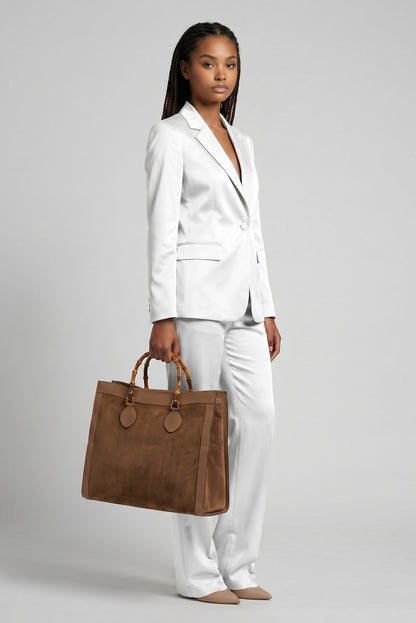Modella in completo bianco indossa una borsa tote Borse Vintage Gucci in camoscio marrone con manici in bambù