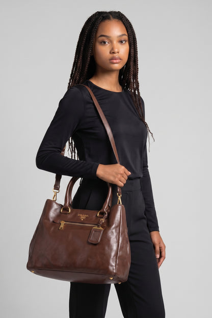 Modella indossa borsa tote Borse Vintage Prada in pelle marrone con dettagli dorati, tracolla e tasca frontale con zip