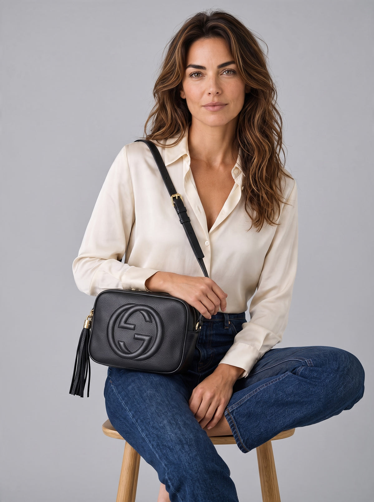 Modella indossa borsa a tracolla Borse Vintage Gucci in pelle nera martellata con logo impresso e nappa decorativa