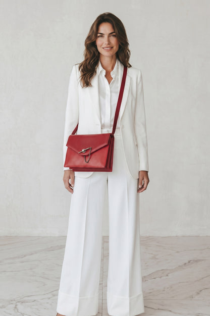 Modella in completo bianco indossa una borsa a tracolla Borse Vintage Gianni Versace in pelle rossa effetto lucertola
