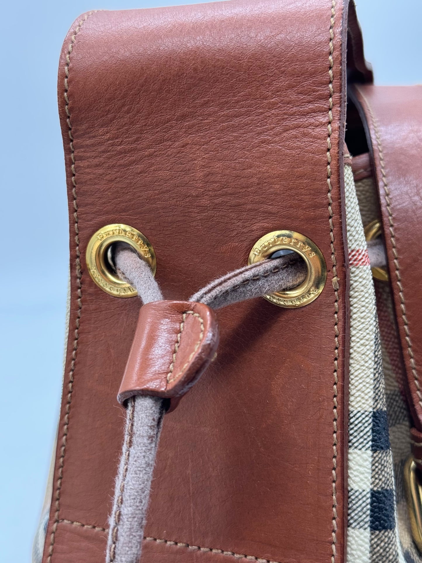 Dettaglio della chiusura a coulisse di una borsa a secchiello Borse Vintage Burberrys in pelle marrone e motivo check