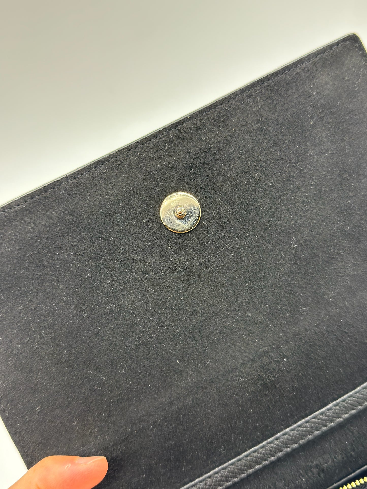 Dettaglio della chiusura magnetica dorata su borsa a tracolla Christian Dior in pelle nera di Borse Vintage