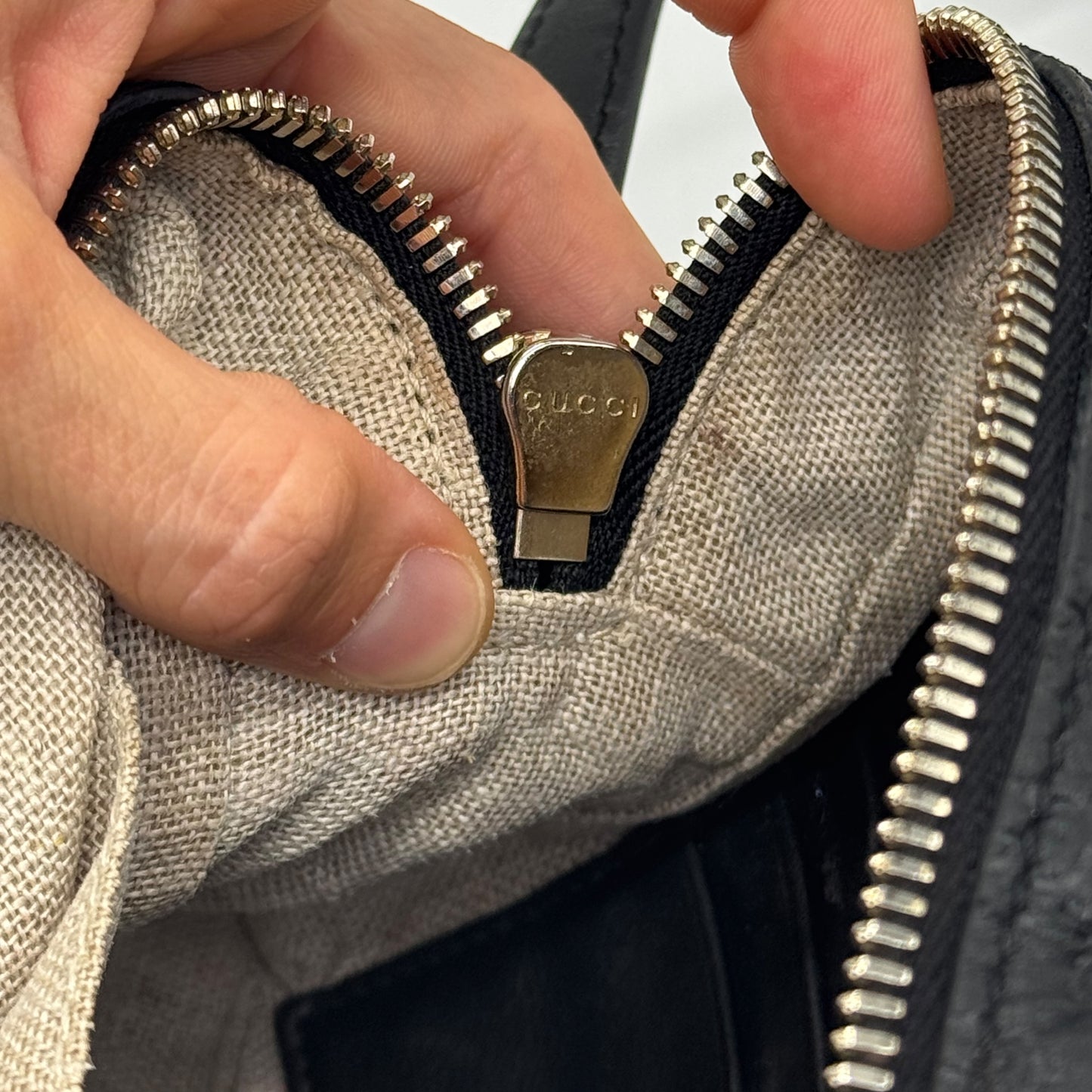Dettaglio della cerniera metallica dorata con logo Gucci su borsa Borse Vintage in pelle nera con interno in tessuto
