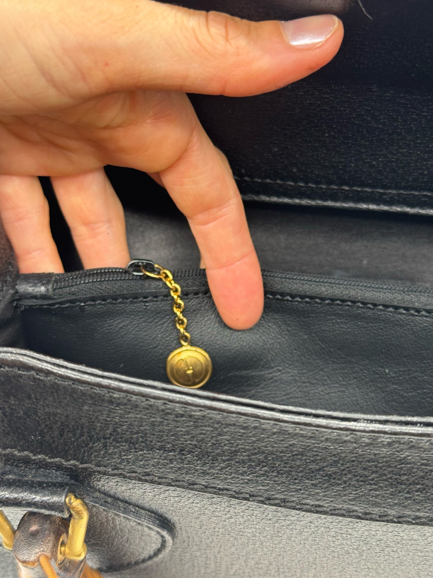 Dettaglio interno della borsa Borse Vintage Gucci in pelle nera con tasca con zip e ciondolo dorato logato