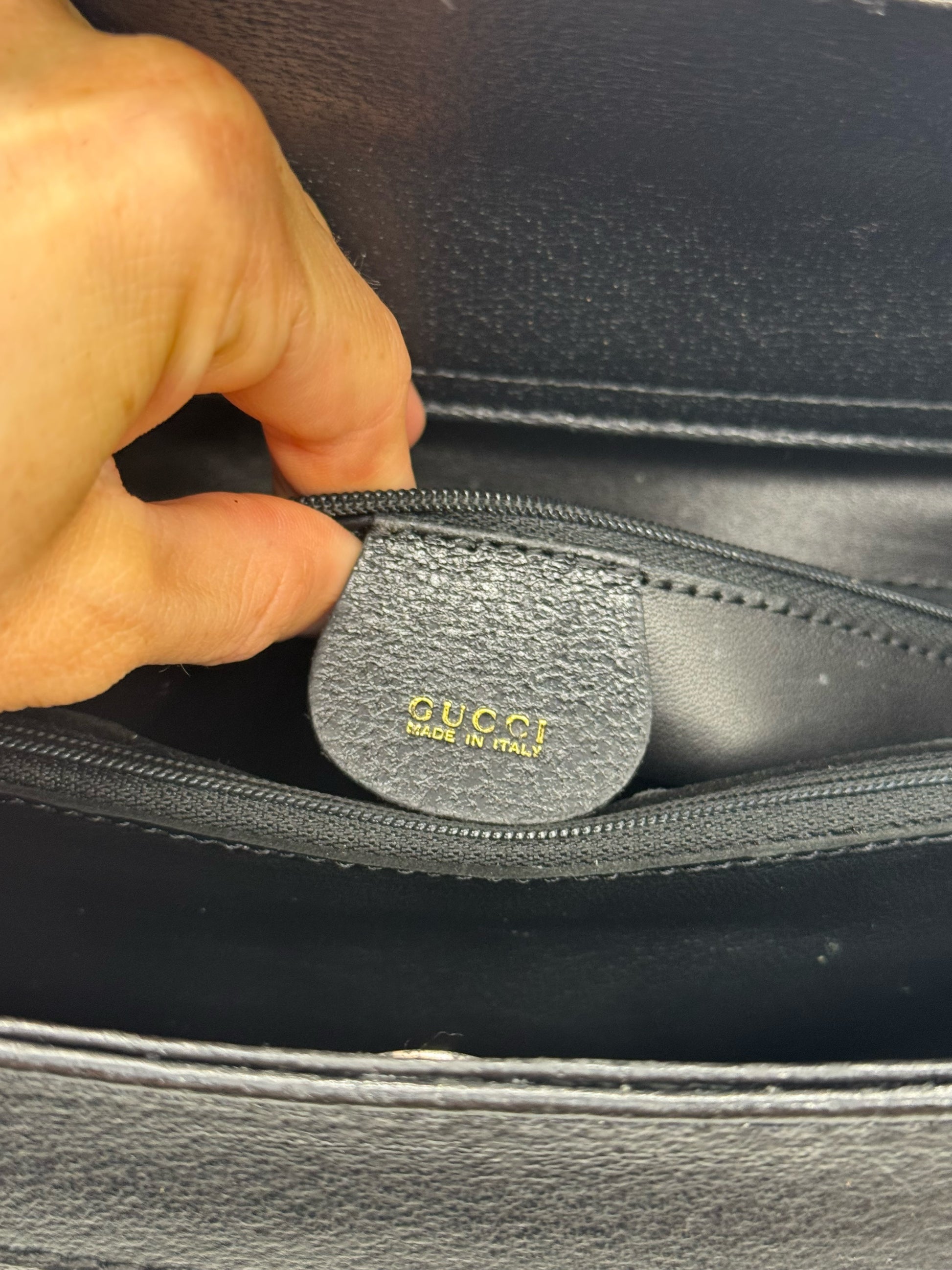 Dettaglio interno della borsa Borse Vintage Gucci in pelle nera con logo impresso e tasca con zip