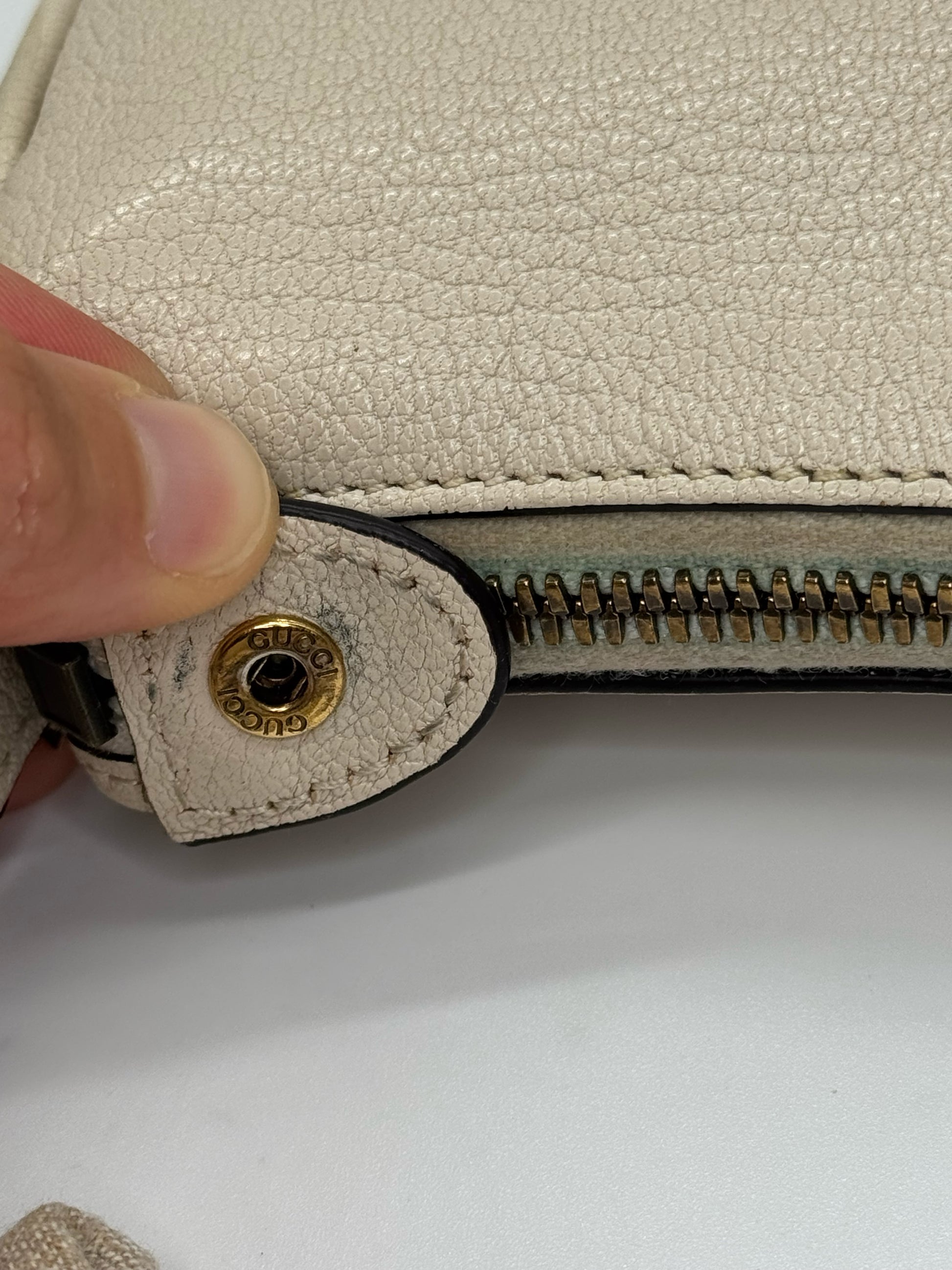 Dettaglio della cerniera e bottone dorato con logo Gucci su borsa a spalla Borse Vintage in pelle martellata avorio
