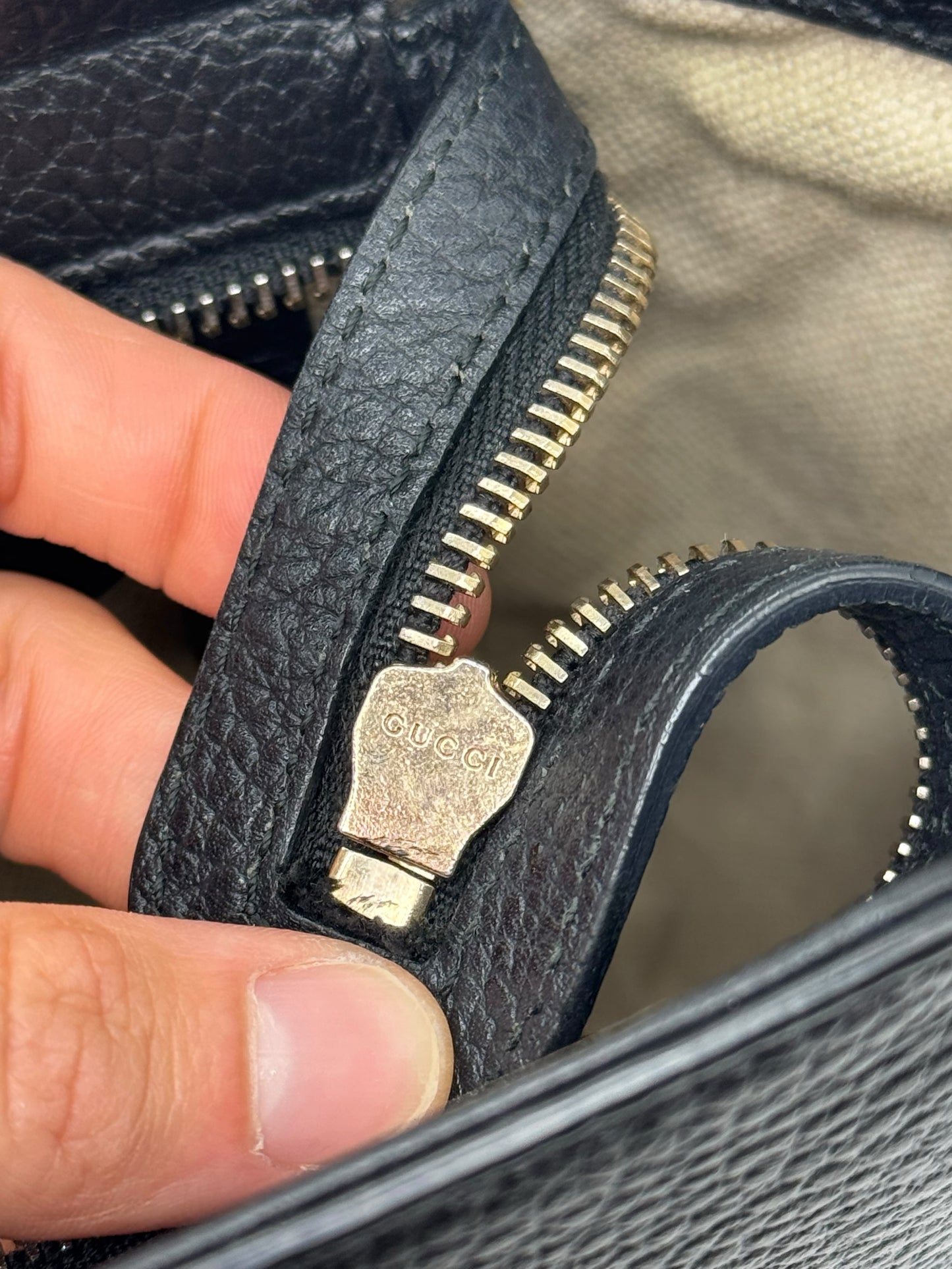 Dettaglio della cerniera in metallo dorato con logo Gucci su borsa in pelle nera martellata Borse Vintage