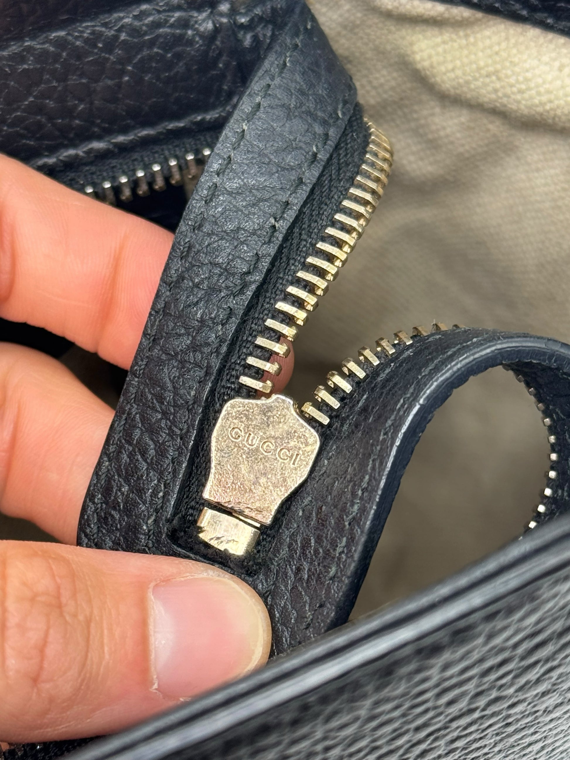 Dettaglio della cerniera in metallo dorato con logo Gucci su borsa in pelle nera martellata Borse Vintage
