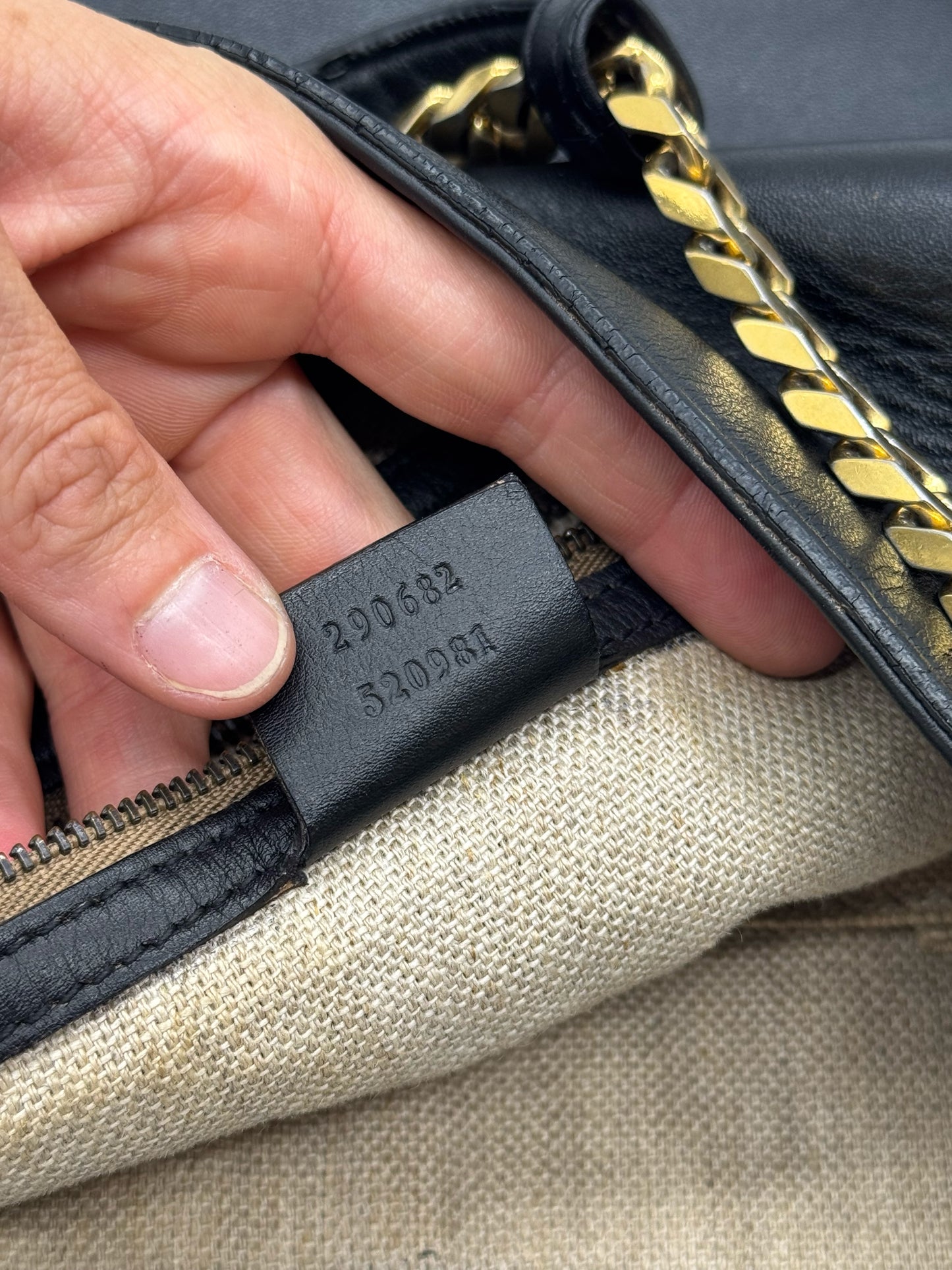 Dettaglio interno della borsa Borse Vintage Gucci in pelle nera con etichetta del numero di serie e tracolla a catena