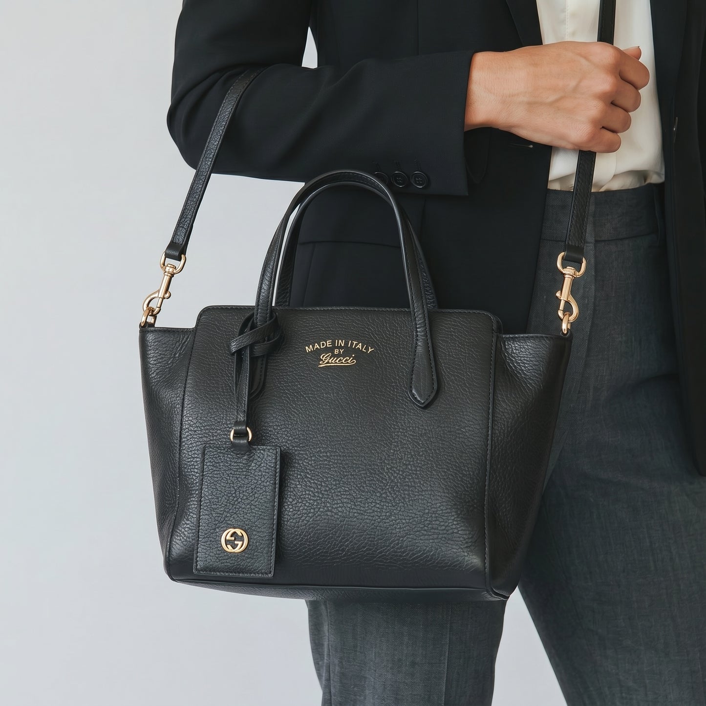 Borsa a mano Borse Vintage Gucci in pelle nera martellata con dettagli dorati e tracolla, indossata da una donna.