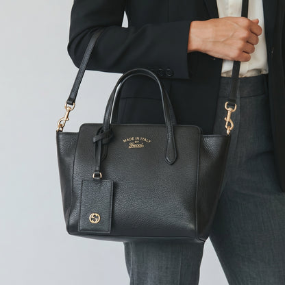 Borsa a mano Borse Vintage Gucci in pelle nera martellata con dettagli dorati e tracolla, indossata da una donna.