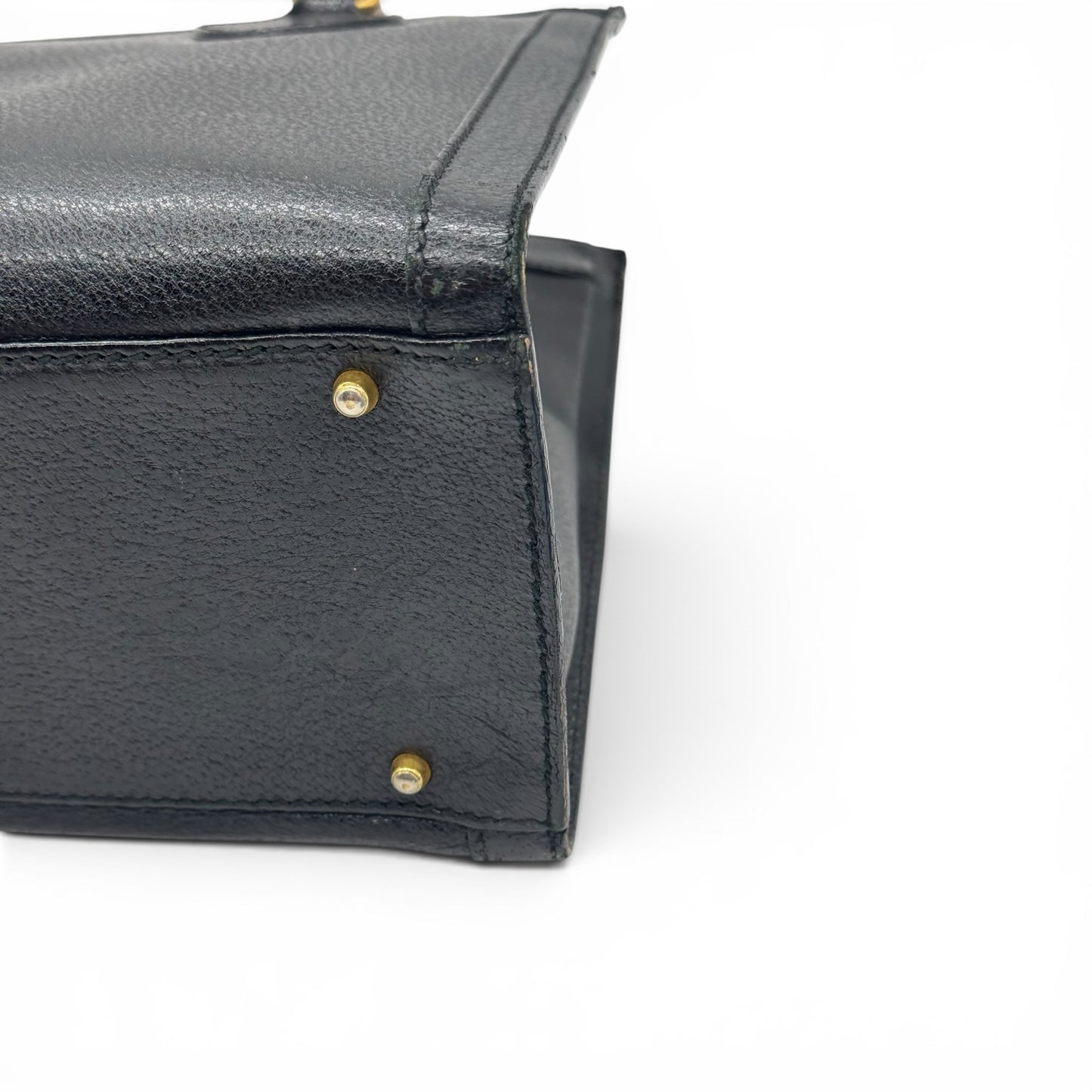 Dettaglio del fondo in pelle nera granulata con piedini protettivi dorati di una borsa Borse Vintage Gucci