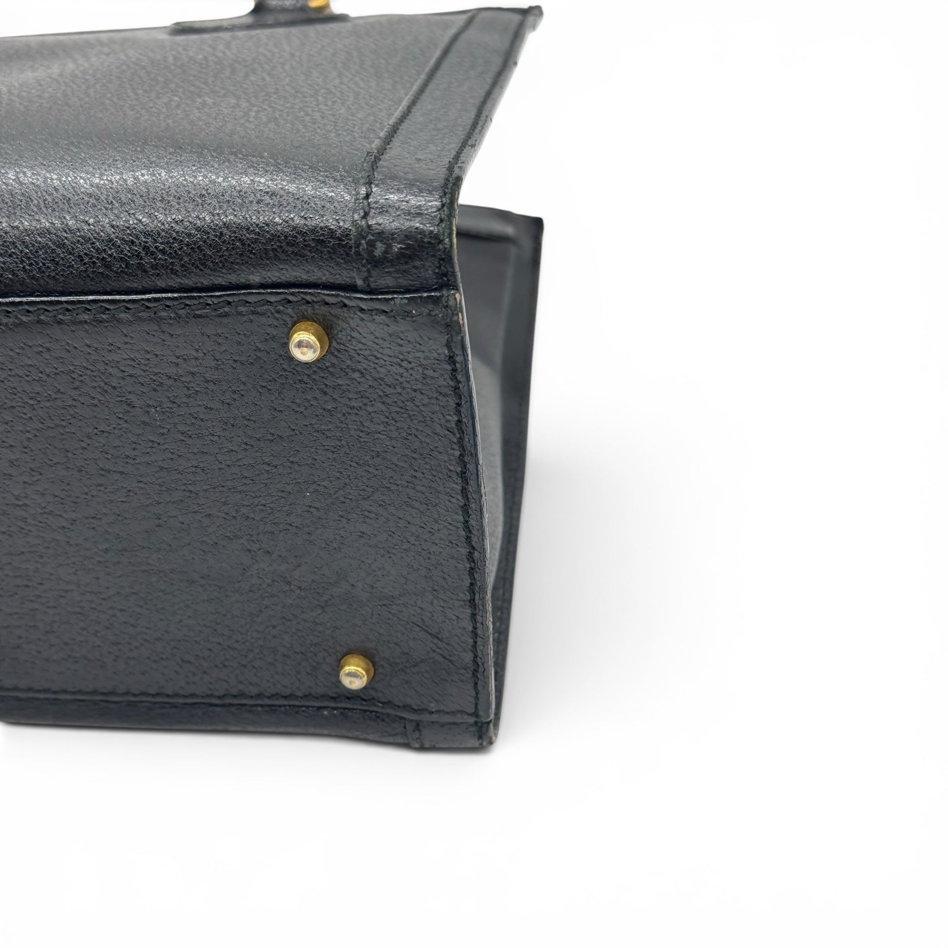 Dettaglio del fondo in pelle nera granulata con piedini protettivi dorati di una borsa Borse Vintage Gucci