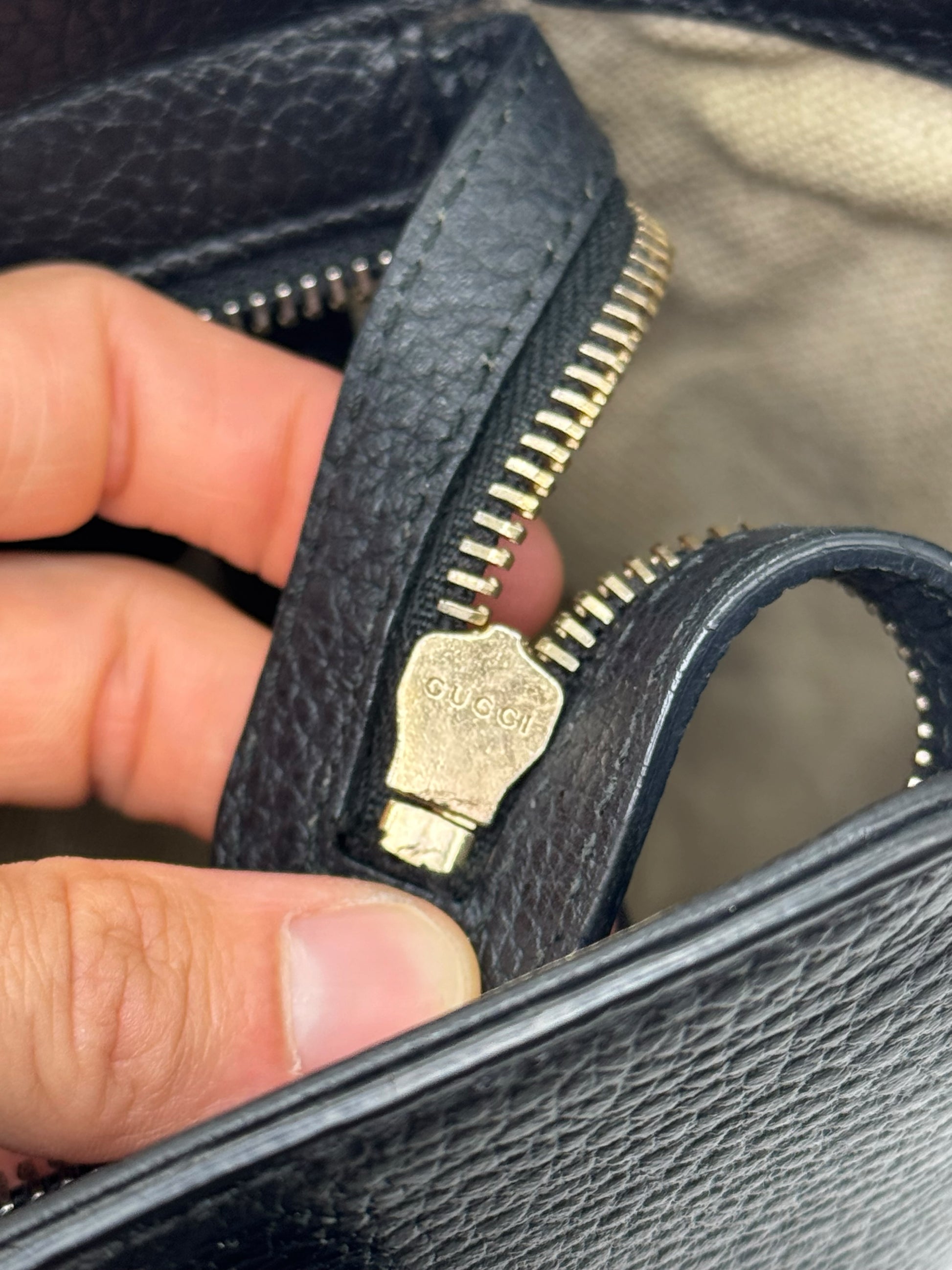 Dettaglio della cerniera in metallo dorato con logo Gucci su borsa in pelle nera martellata Borse Vintage