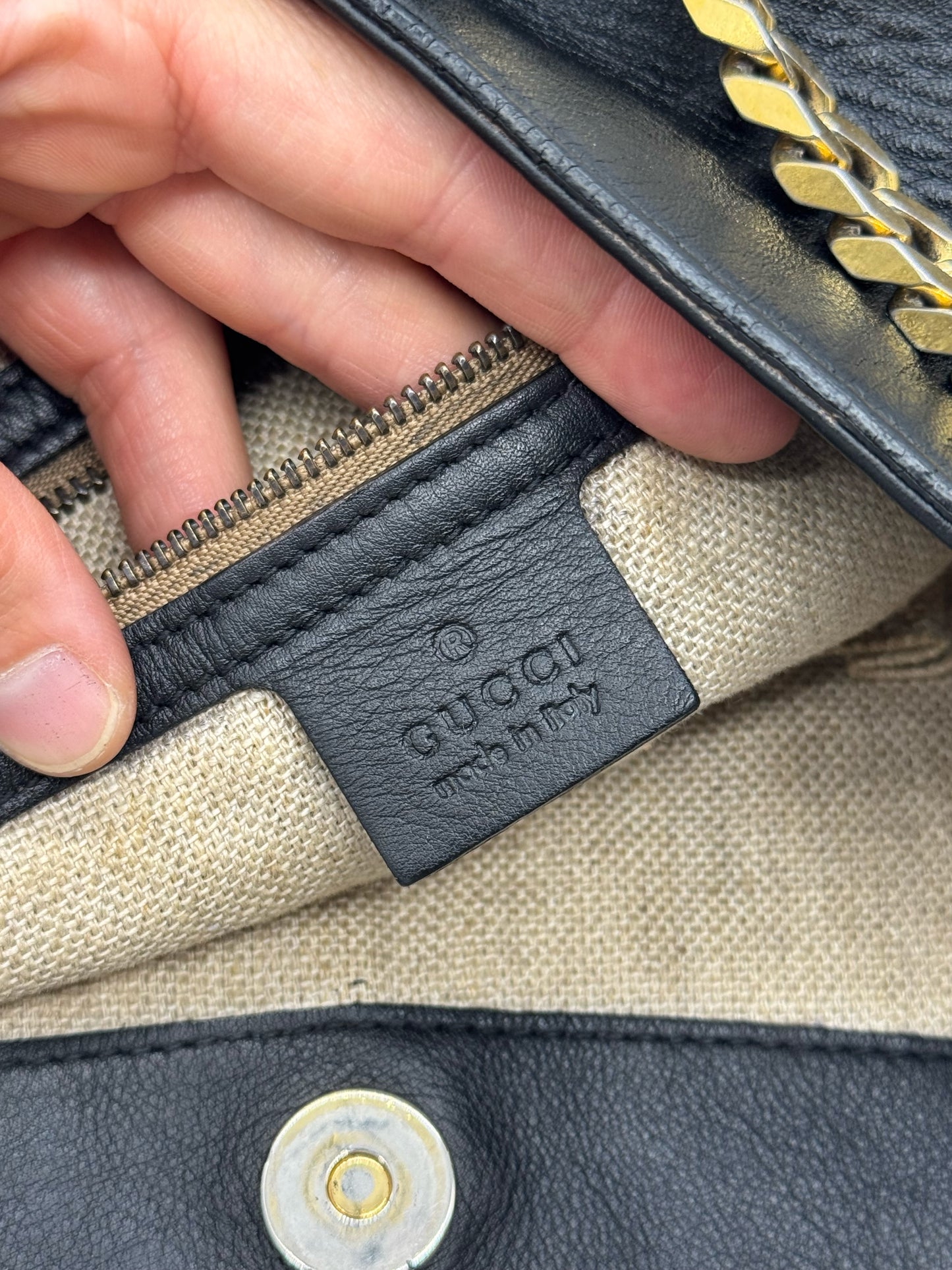 Dettaglio interno della borsa Borse Vintage Gucci in pelle nera con etichetta logo impressa e tracolla a catena dorata