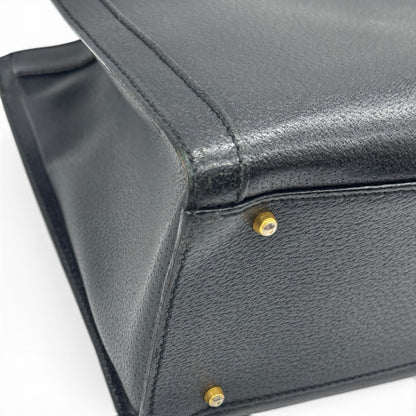 Dettaglio del fondo in pelle nera granulata con piedini protettivi dorati di una borsa Borse Vintage Gucci