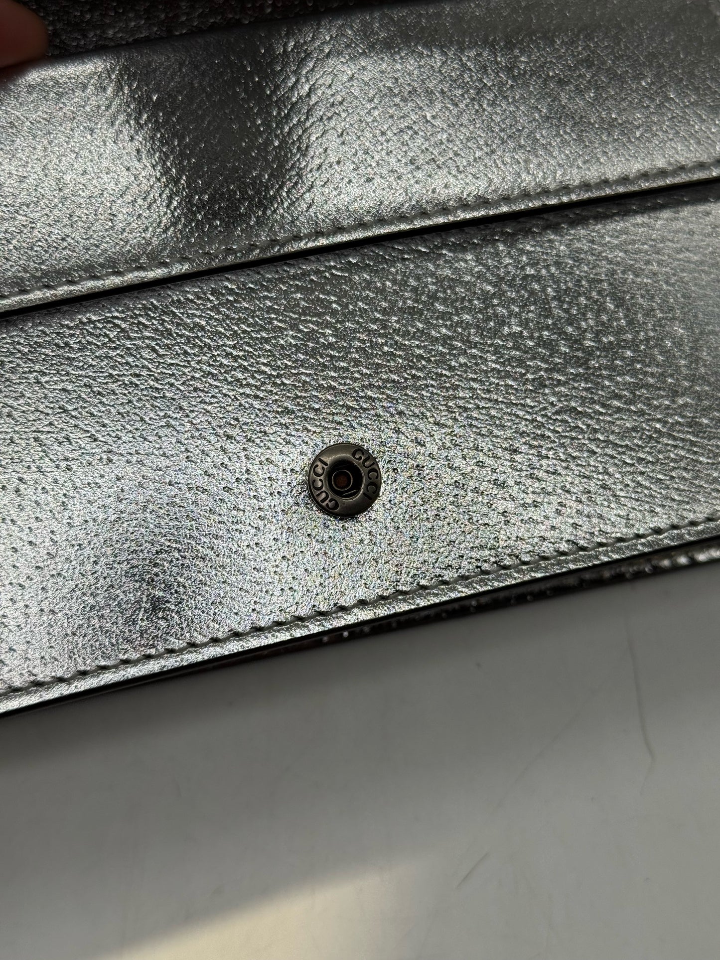 Dettaglio del bottone a pressione con logo Borse Vintage su pelle metallizzata argento della borsa Gucci Dionysus