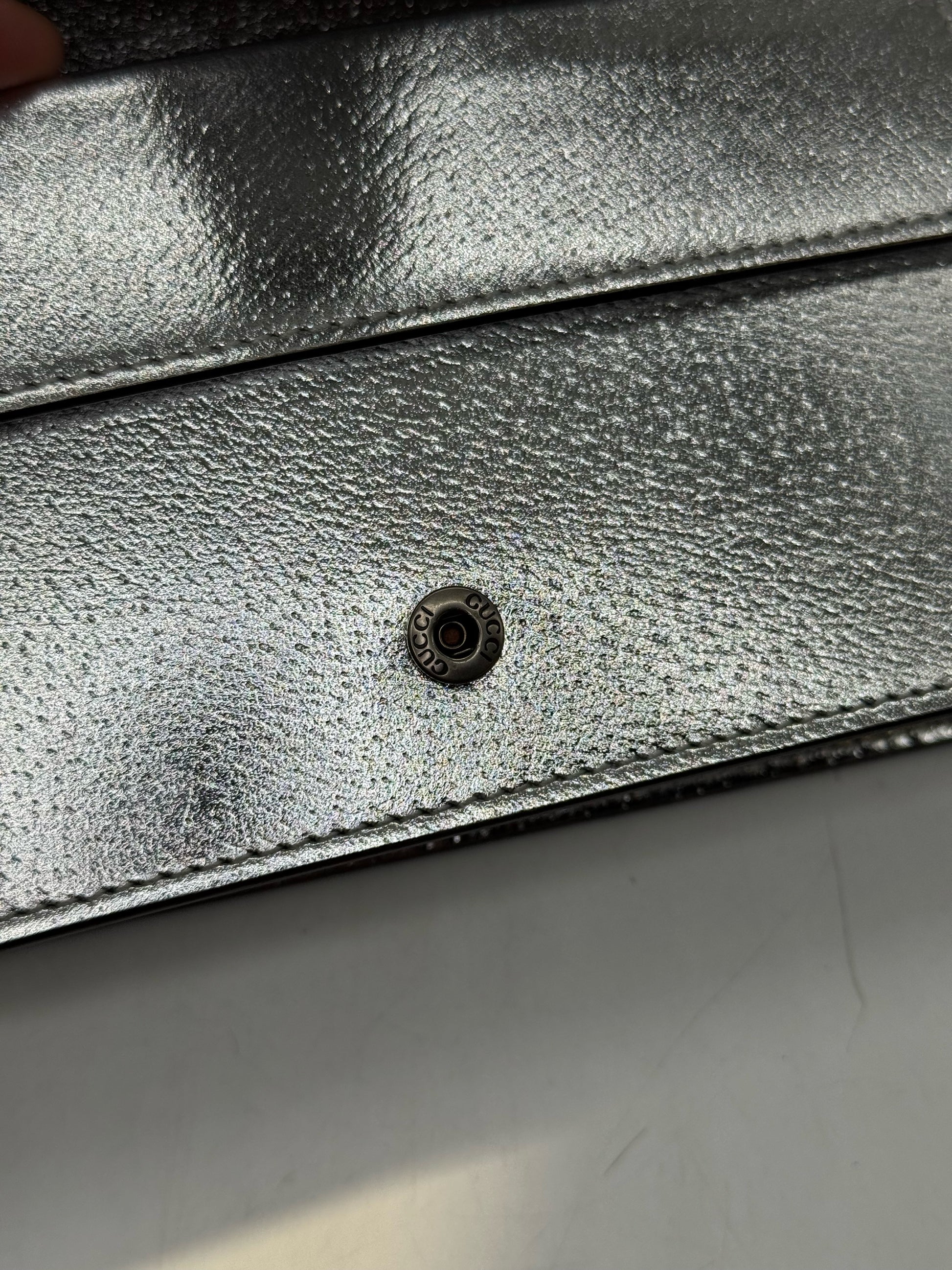 Dettaglio del bottone a pressione con logo Borse Vintage su pelle metallizzata argento della borsa Gucci Dionysus