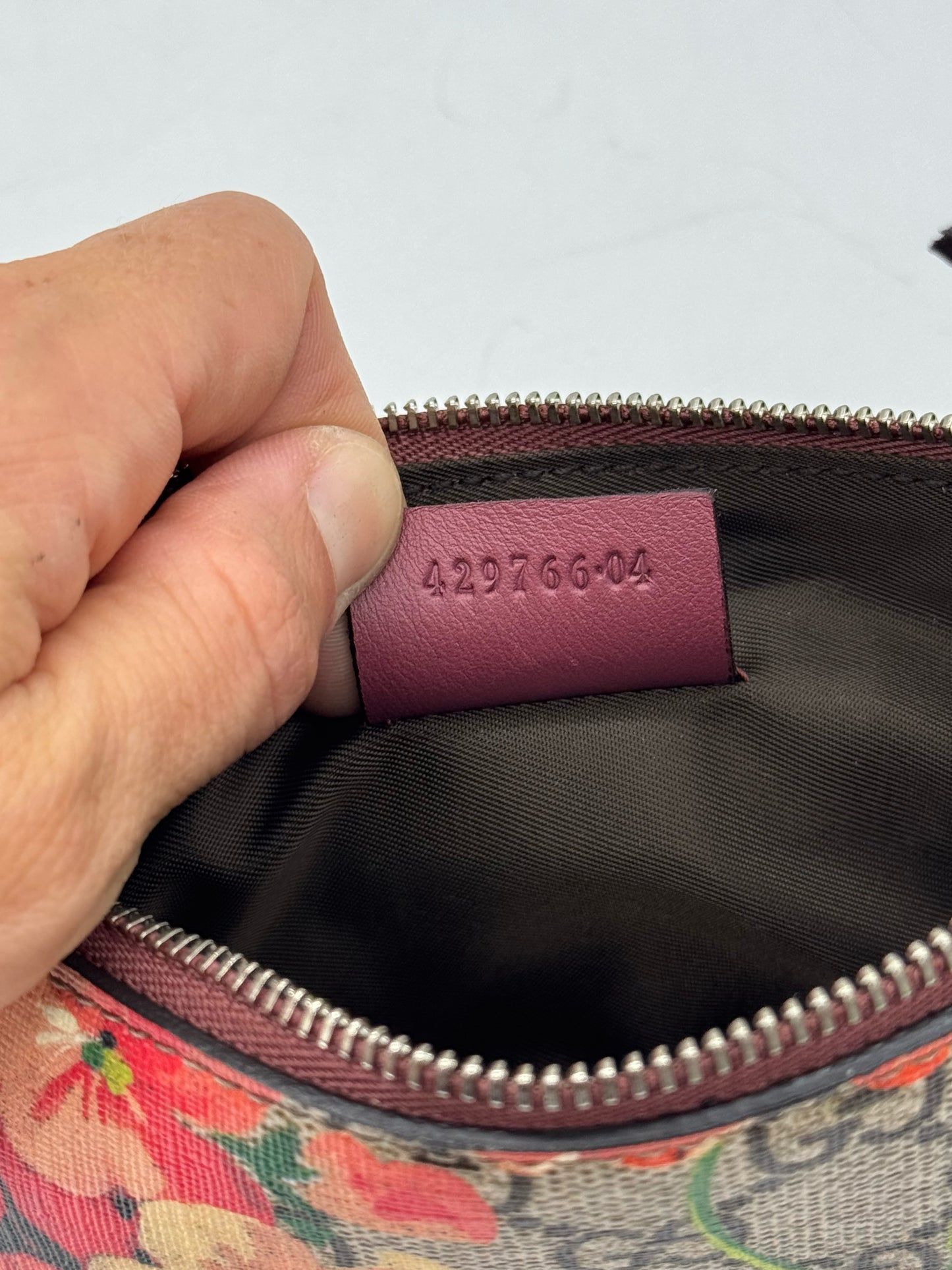 Etichetta interna in pelle bordeaux con codice seriale di una pochette Borse Vintage Gucci in tela floreale