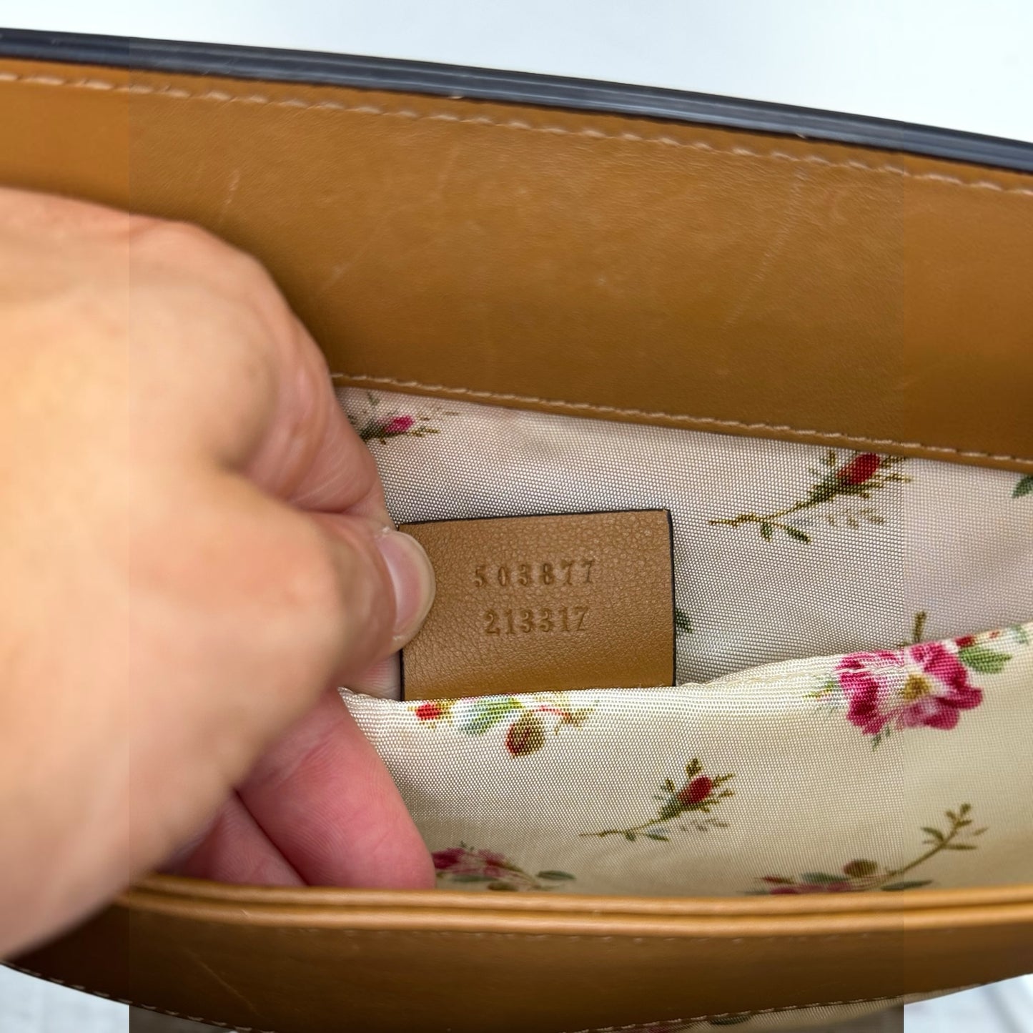Dettaglio interno borsa Borse Vintage Gucci con etichetta in pelle, codice seriale e fodera in tessuto floreale.