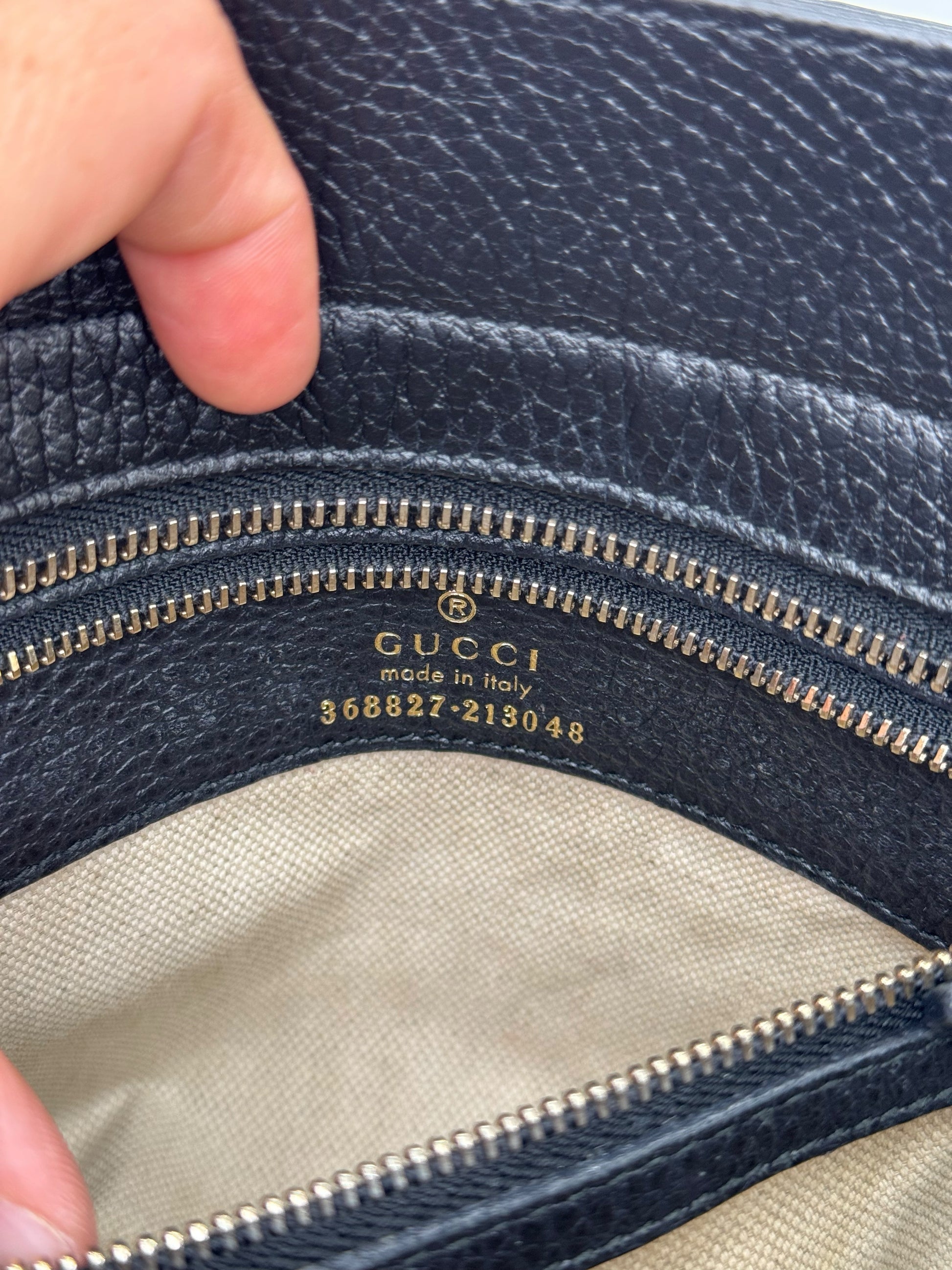 Dettaglio interno di borsa Borse Vintage Gucci in pelle nera con logo impresso e codice seriale dorato