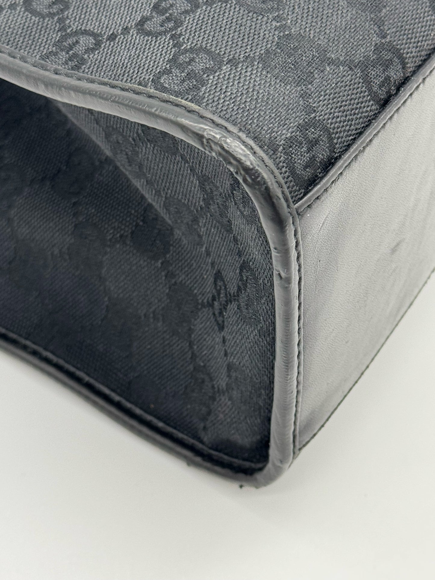 Dettaglio dell'angolo di una borsa Borse Vintage Gucci Jackie in tessuto nero con motivo GG e finiture in pelle