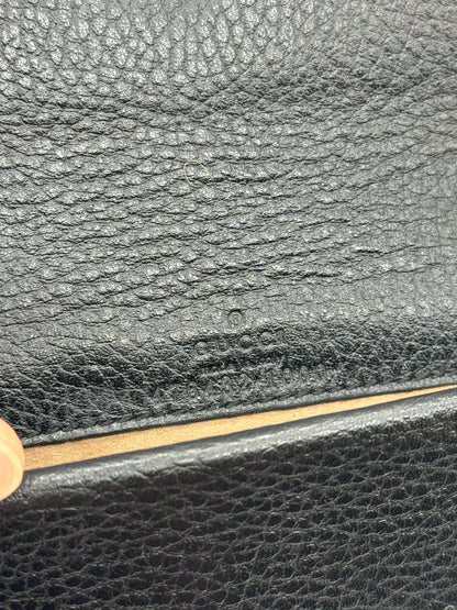 Dettaglio del logo Gucci impresso su pelle nera martellata della borsa Dionysus proposta da Borse Vintage