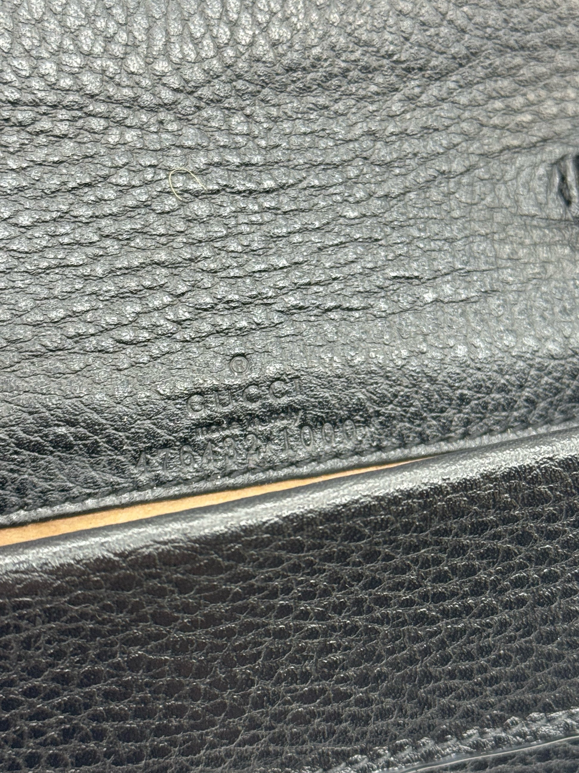 Dettaglio del logo Gucci impresso su pelle nera martellata della borsa Borse Vintage Dionysus