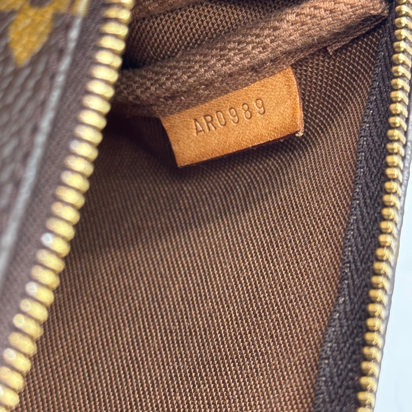 Dettaglio interno della pochette Borse Vintage Louis Vuitton con etichetta in pelle e codice di autenticazione