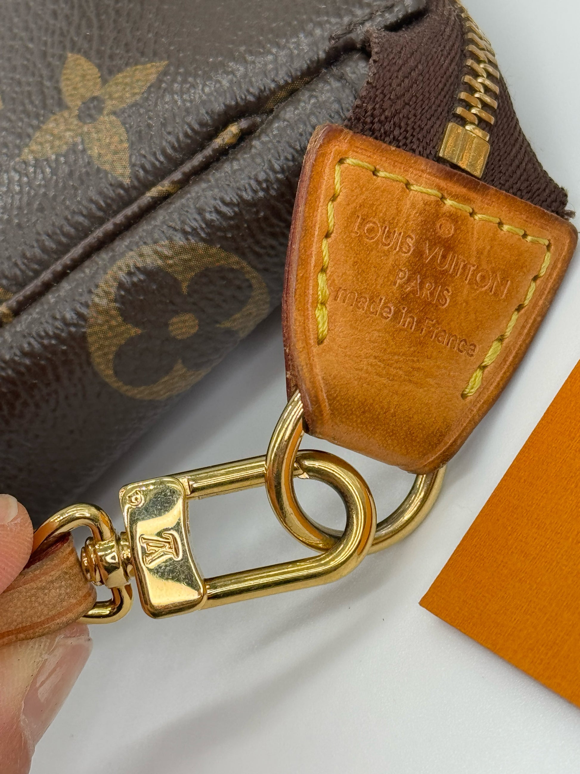 Dettaglio del moschettone dorato e logo impresso su pelle vacchetta della pochette Borse Vintage Louis Vuitton Monogram
