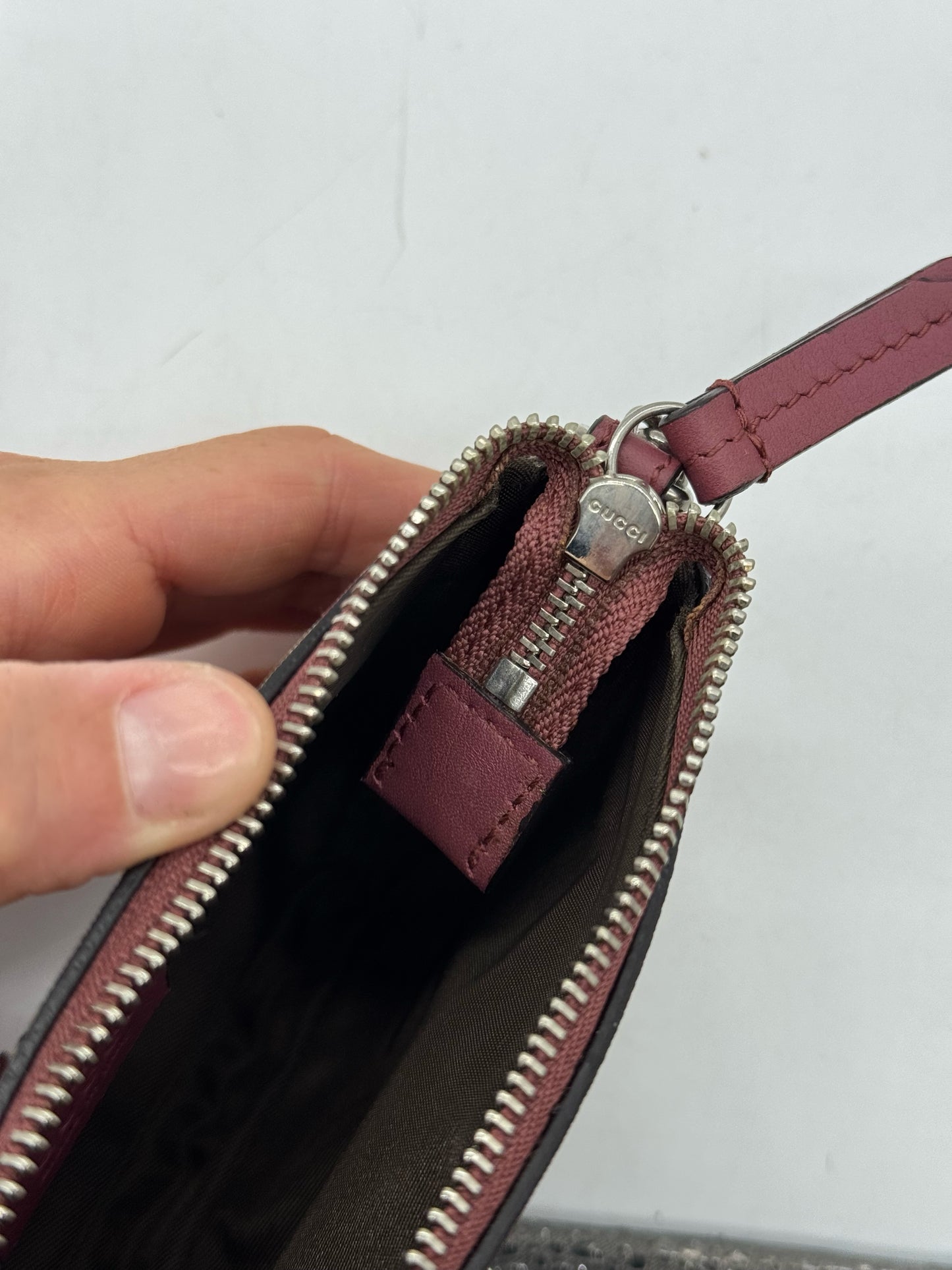 Dettaglio della cerniera metallica con logo Gucci su pochette Borse Vintage in pelle bordeaux e tela GG Supreme
