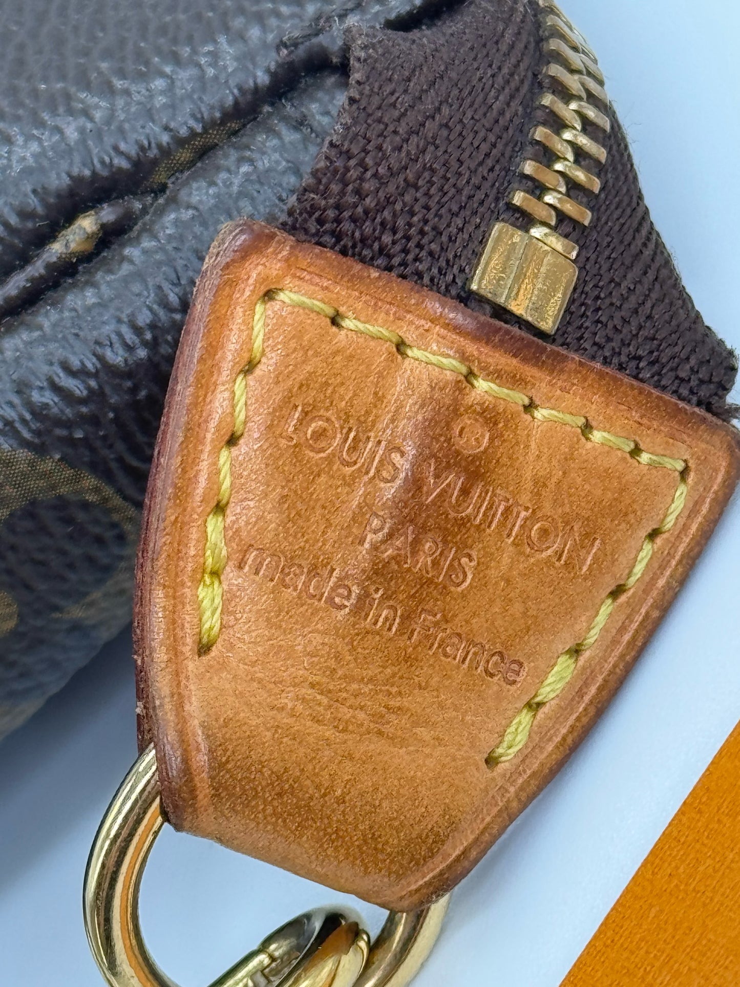 Dettaglio in pelle vacchetta con logo impresso Borse Vintage su pochette Louis Vuitton in tela Monogram marrone