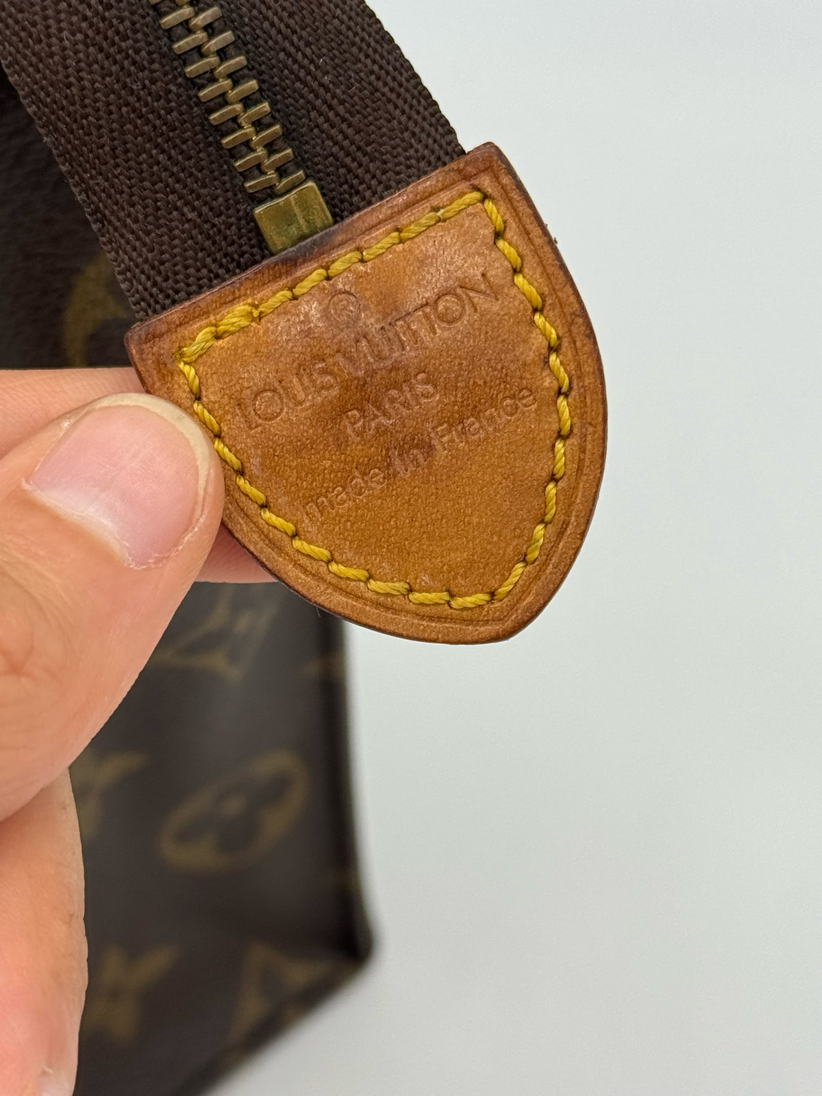 Dettaglio della linguetta in pelle con logo Louis Vuitton su pochette Borse Vintage in tela Monogram marrone