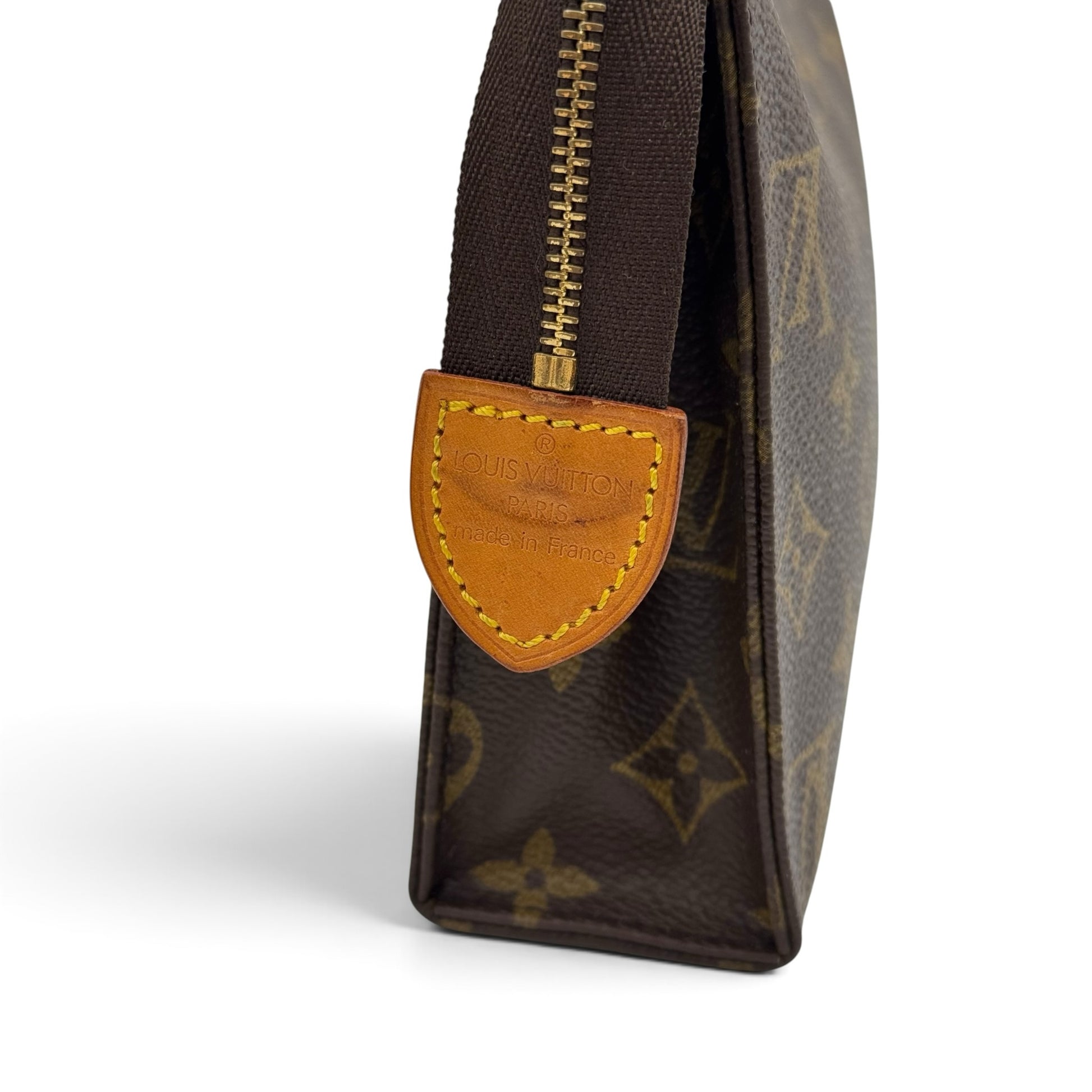 Dettaglio laterale della pochette Borse Vintage Louis Vuitton in tela Monogram con zip e targhetta in pelle naturale