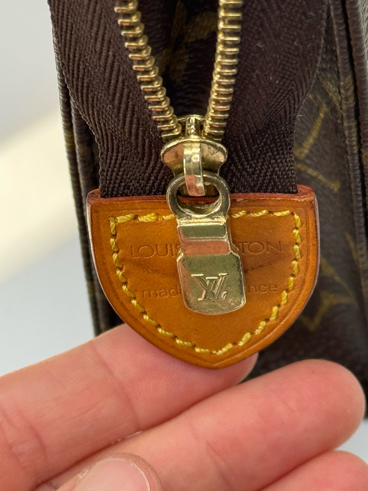 Dettaglio della chiusura a zip dorata e linguetta in pelle della pochette Borse Vintage Louis Vuitton in tela Monogram