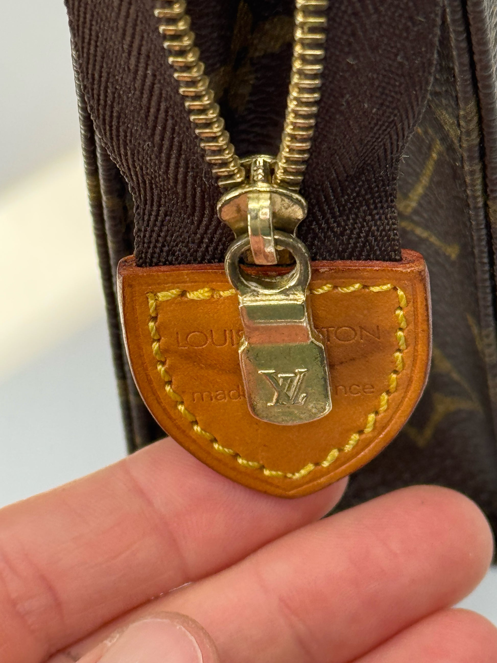 Dettaglio della chiusura a zip dorata e linguetta in pelle della pochette Borse Vintage Louis Vuitton in tela Monogram
