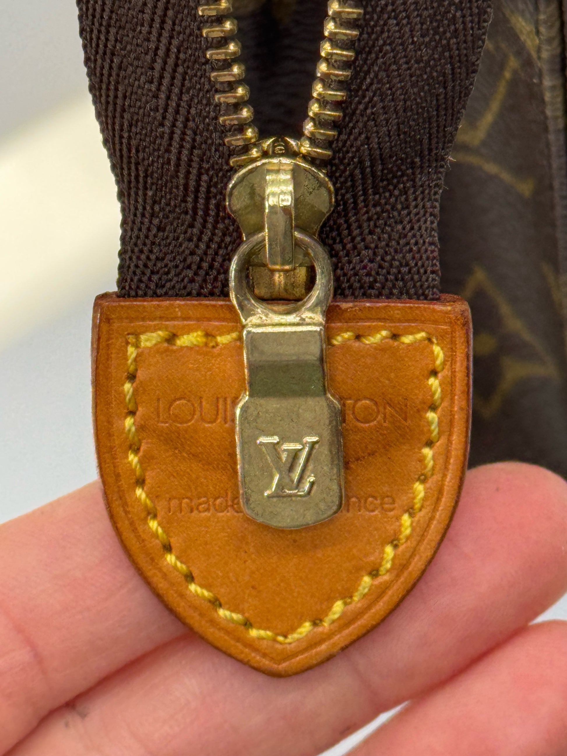 Dettaglio della zip dorata e linguetta in pelle con logo Louis Vuitton su pochette Borse Vintage in tela Monogram
