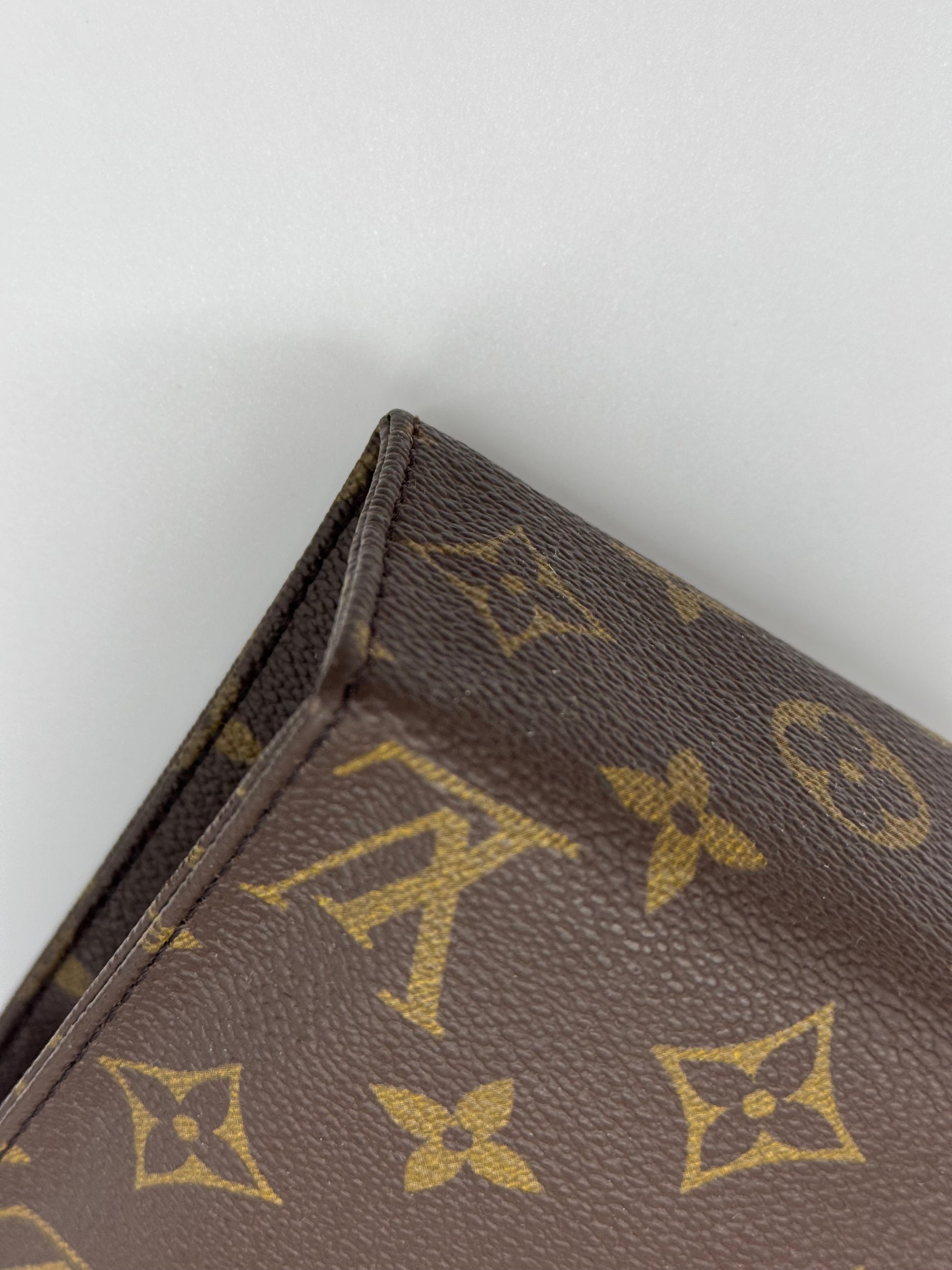 Dettaglio della tela Monogram marrone su pochette Borse Vintage, iconico motivo Louis Vuitton con texture resistente.