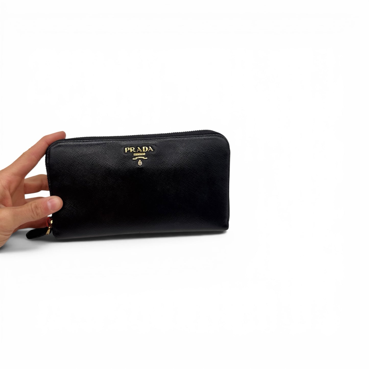 Portafoglio lungo Borse Vintage Prada in pelle Saffiano nera con logo dorato e chiusura zip, tenuto in mano.