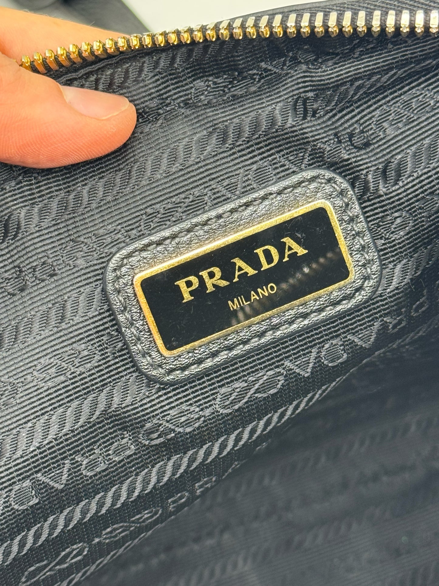 Dettaglio interno della borsa Borse Vintage Prada con etichetta logo in metallo dorato su fodera logata nera