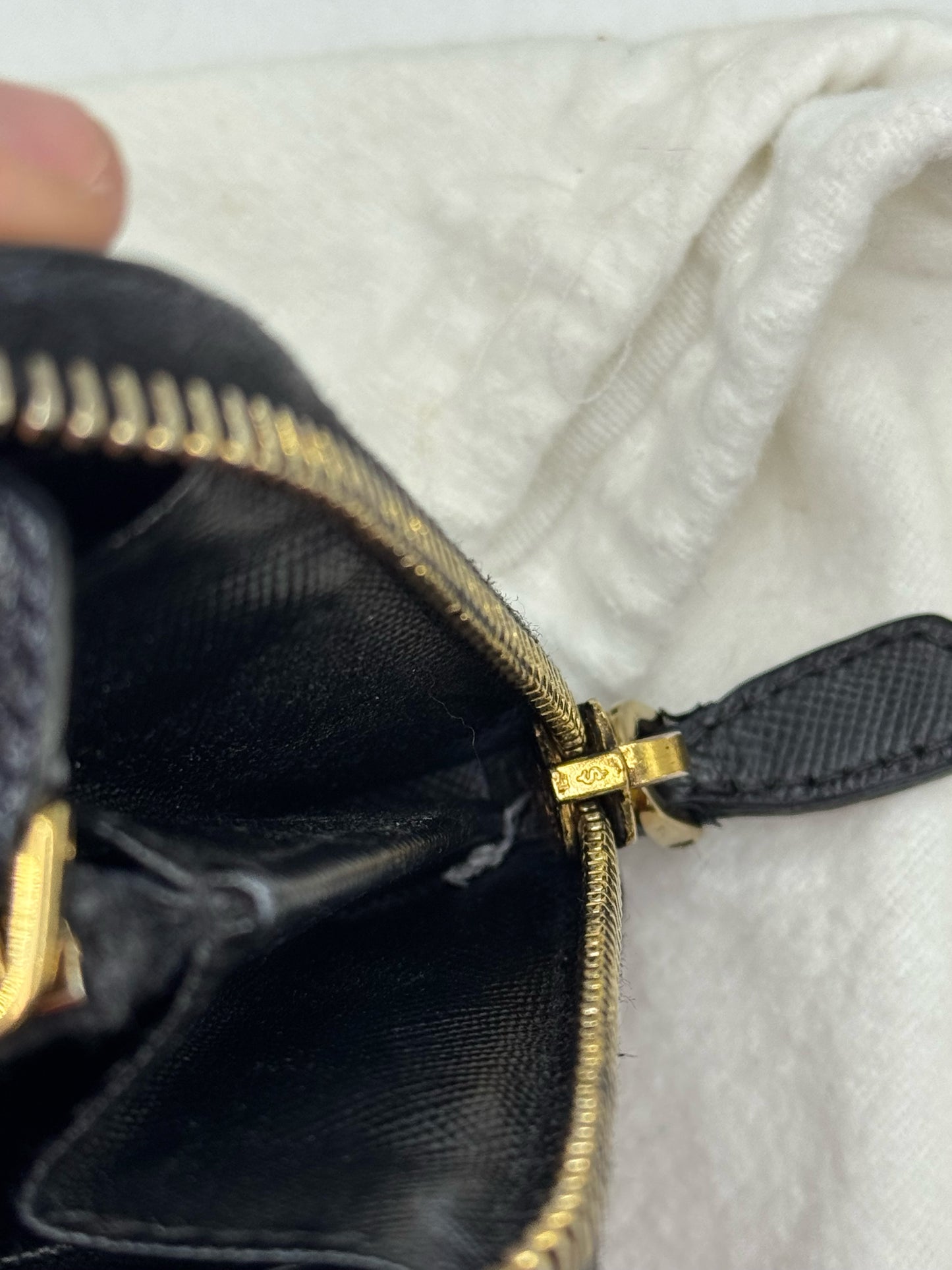 Dettaglio della cerniera dorata e interno in pelle nera di un portafoglio Prada autentico da Borse Vintage